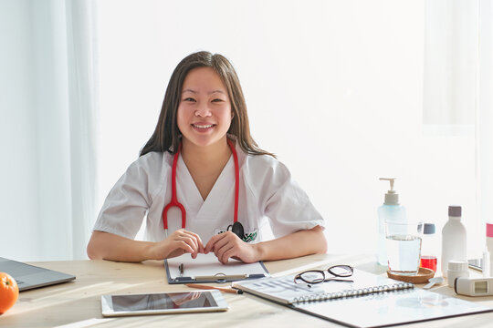 Stock photo of healthcare professional working from her desk smiling and looking at camera.