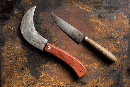 Top view of sharp knives with shabby blades placed on rusty metal table