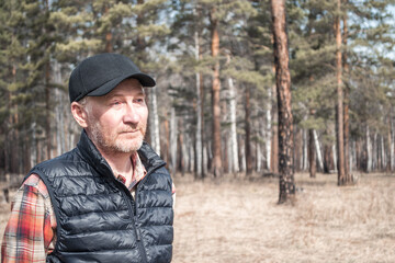 Naklejka na ściany i meble Portrait of a handsome middle-aged man in a cap. Adult man in shirt and vest outdoors in the park. Copy space.