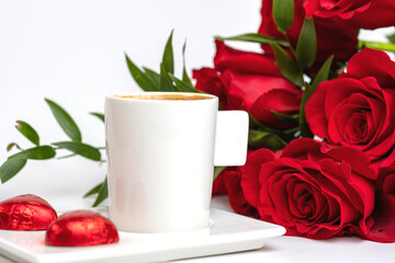 cup of coffee and a bouquet of red roses on a white table
