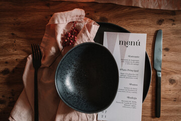 From above of paper sheet with menu list near bowl on textile and burning candles during festive occasion in cafe