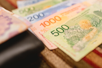 Money, Argentinian peso. Argentine money bills on a colorful upholstery. Photography represents...