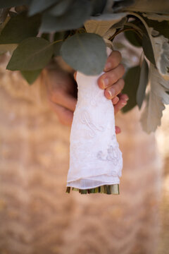 Bride Holding Bridal Bouquet Wrapped in a Sentimental Handkerchief Displaying its Significance and Intricate embroidery