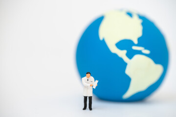 Global Healthcare Concept. Doctor miniature figure people with patient clipboard standing with mini world ball as background.