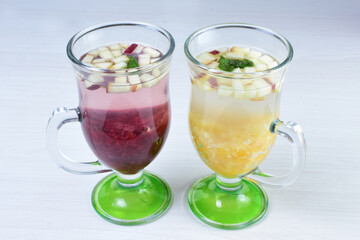 Colorful italian sodas with chopped fruits on white wooden background