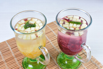Colorful italian sodas with chopped fruits on white wooden background