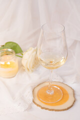 Glass of white wine, rose and candle on a white background. 8th march and valentine's day concept