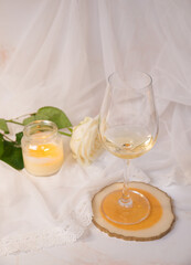 Glass of white wine, rose and candle on a white background. 8th march and valentine's day concept