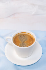 white cup of coffee on blue cloth