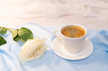 White rose with a Cup of coffee on a blue background. concept of march 8 and valentine.