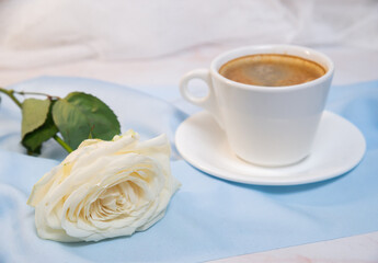 White rose with a Cup of coffee on a blue background. concept of march 8 and valentine.