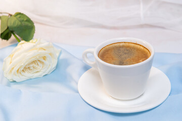 White rose with a Cup of coffee on a blue background. concept of march 8 and valentine.