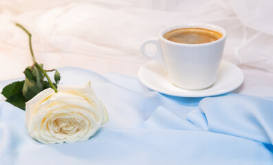 Fototapeta na wymiar White rose with a Cup of coffee on a blue background. concept of march 8 and valentine.