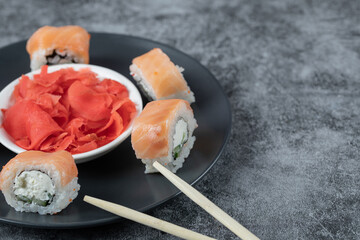 Salmon rolls in a black platter with marinated red ginger