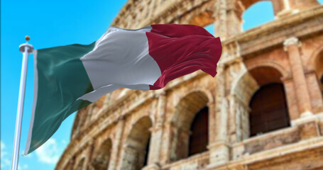 The Italian flag flapping in the wind with the Colosseum blurred in the background