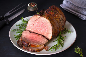 Sliced roast beef with herbs on plate. Horizontal photo