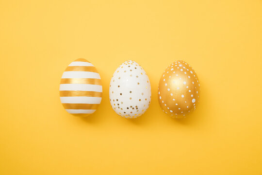 Easter golden decorated eggs on yellow background. Minimal easter concept. Happy Easter card with copy space for text. Top view, flatlay