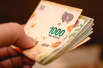 Peso Argentino. Dinheiro, Argentina, Finanças e economia. Uma pessoa segurando notas do dinheiro da Argentina.  - obrazy, fototapety, plakaty