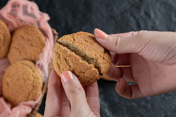 Cutting crispy oatmeal cookie into half in the hand