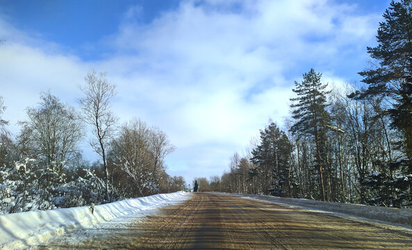 highway with horizon on blue sky and clouds in the daytime at winter with snow covered trees