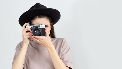 European woman holding retro photocamera and taking a photo over white background in studio