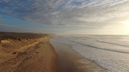 Vue aérienne artistique de la plage avec vagues et dune au coucher du soleil