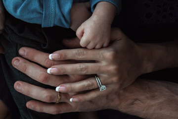 Mom, dad and newborn baby's hands close up. Togetherness, harmony, family bond values.