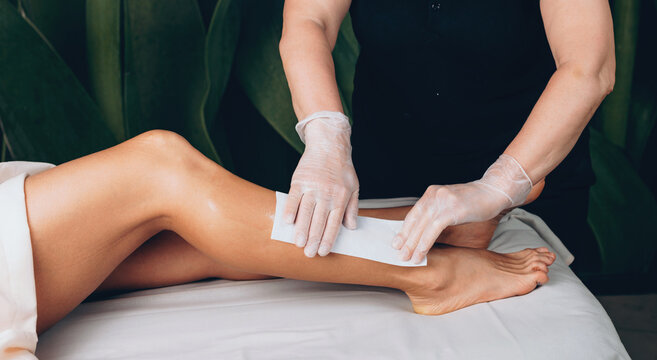 Side view photo of a caucasian woman having a spa procedure of leg hair depilation