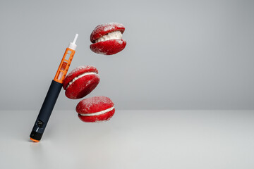 Insulin syringe and red macaroon cakes on a gray background. Trending style levitation. Diabetes...