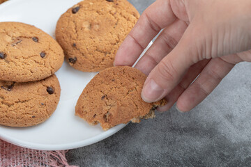 Taking a piece of oatmeal cookie from white saucer