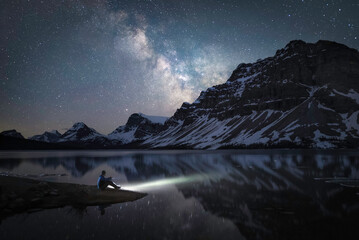 A man on the shore of Bow Lake in the Canadian Rockies viewing the Milky Way during an early Summer night.