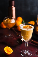 Goblet glass containing a whiskey sour garnished with a dried orange