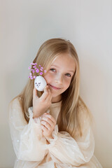 kid holding hands Cute Easter eggs with drawn faces and floral purple wreath