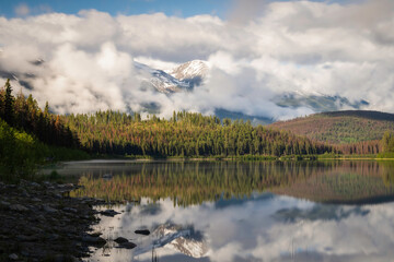 Fototapeta premium Fog rolling about the Canadian Rockies in Jasper National Park on a beautifully tranquil early Summer morning at Patricia Lake.