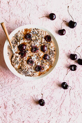 Overnight oats topped with halved cherries and spoon in white bowl