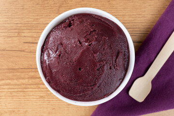 Brazilian frozen açai berry ice cream bowl. with fruits on wooden background. Summer menu front view