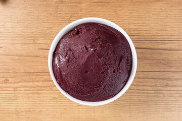Brazilian frozen açai berry ice cream bowl. with fruits on wooden background. Summer menu top view
