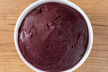 Brazilian frozen açai berry ice cream bowl. with fruits on wooden background. Summer menu top view