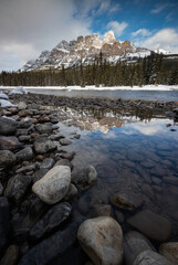 Castle Mountain in Banff National Park reflecting in a small pool alongside the Bow River during a Winter afternoon.