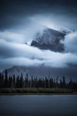 Fotobehang Mistig bos Mount Rundle in Banff shrouded in moody clouds and fog as viewed from Vermilion Lakes in late September. 