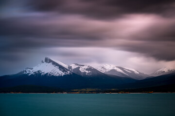 Fototapeta na wymiar A long exposure of stormy skies over Abraham Lake and the Canadian Rockies with Kista Peak on the left.