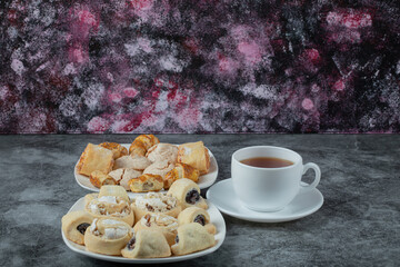 Variety of cookies in the platter with a cup of tea aside