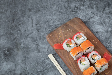 Sushi maki with red caviar and cream cheese on a wooden board