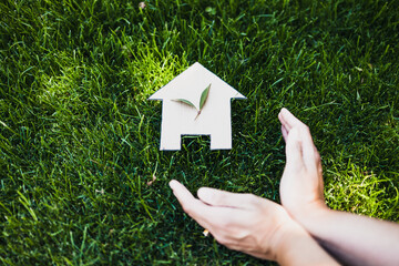green home and eco-friendly construction, house icon on green grass lawn under the sun with two...