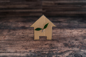 Obraz na płótnie Canvas green home and energy efficiency, ecological house icon with leaves on it on wooden background