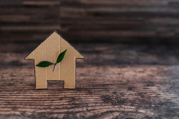 Obraz na płótnie Canvas green home and energy efficiency, ecological house icon with leaves on it on wooden background
