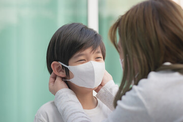 Asian mother puts a safety mask on her son's face