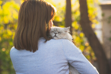 Asian woman holding her cat in the light of sunset © lalalululala