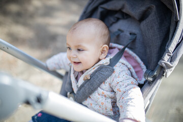 Adorable and happy baby in a stroller with blurry background