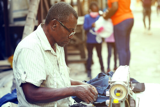 image of aged african man, in front of sewing machine- outdoor business concept               